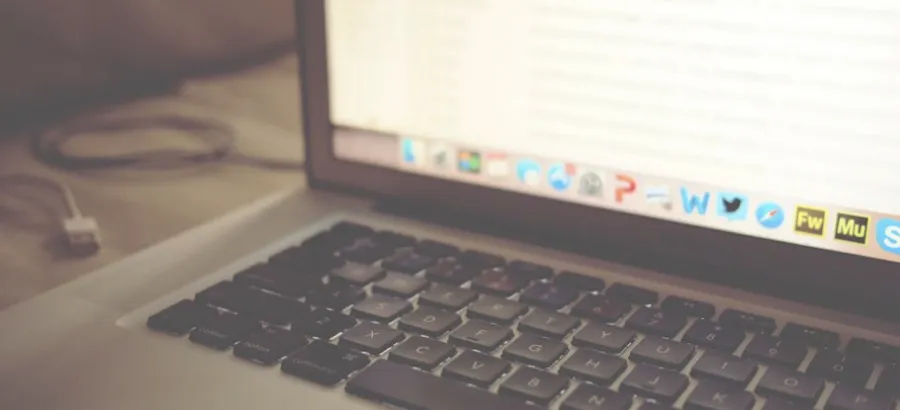 Close-up of a silver laptop keyboard and screen on a desk