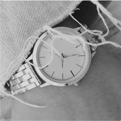 Silver wristwatch with a white face on a wrist with a knit sweater sleeve