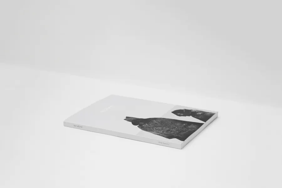 A closed paperback book lying on a bright white table in soft light