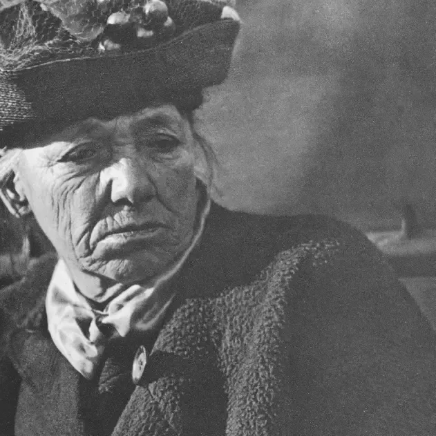Black and white portrait from 1916 of an older woman in a dark hat and coat looking to the side
