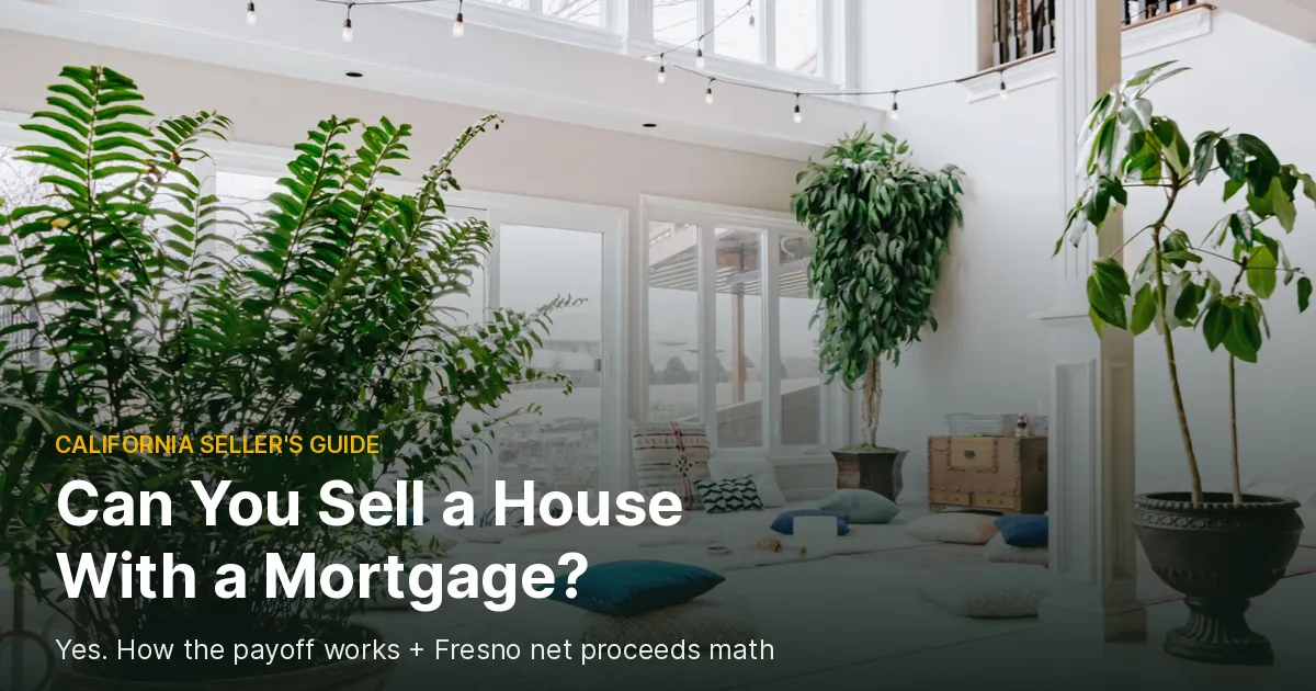 Bright white living room with tall windows, string lights and large potted plants, cover photo for a guide on whether you can sell a house with a mortgage