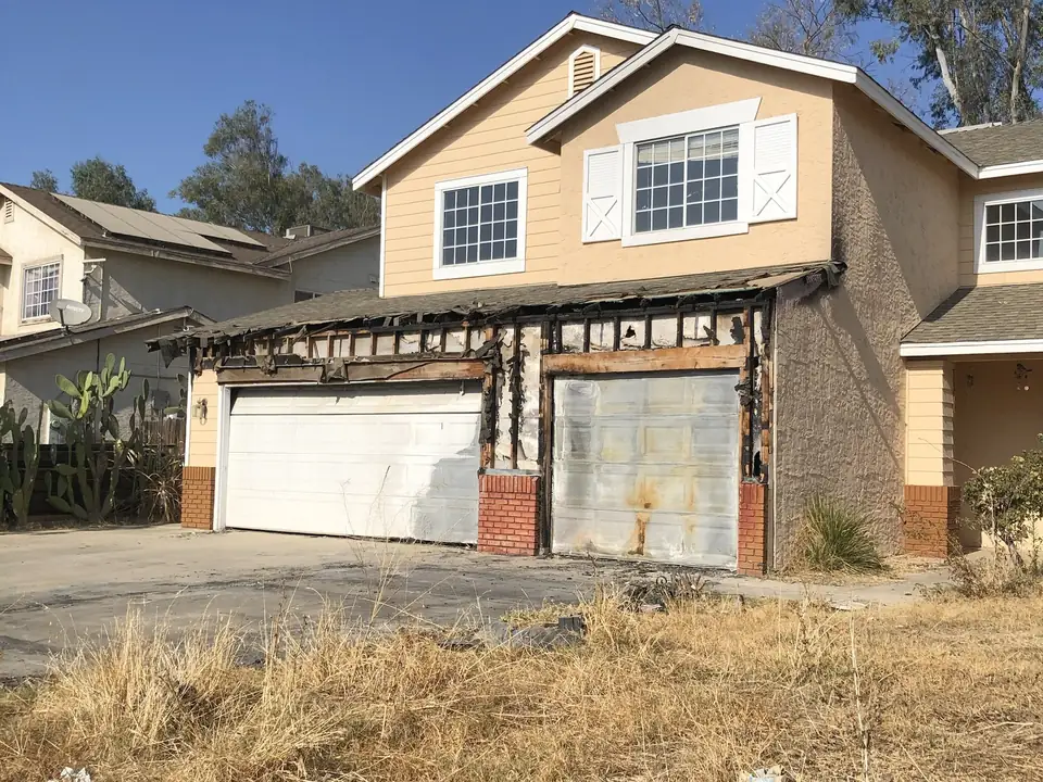Two-story house with a fire-damaged garage, from a Cash For Houses Fresno transaction